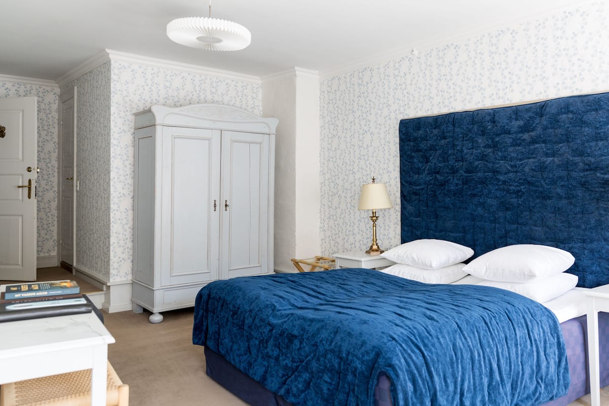 Une chambre à coucher avec un grand lit, une armoire blanche et une table de chevet avec une lampe.