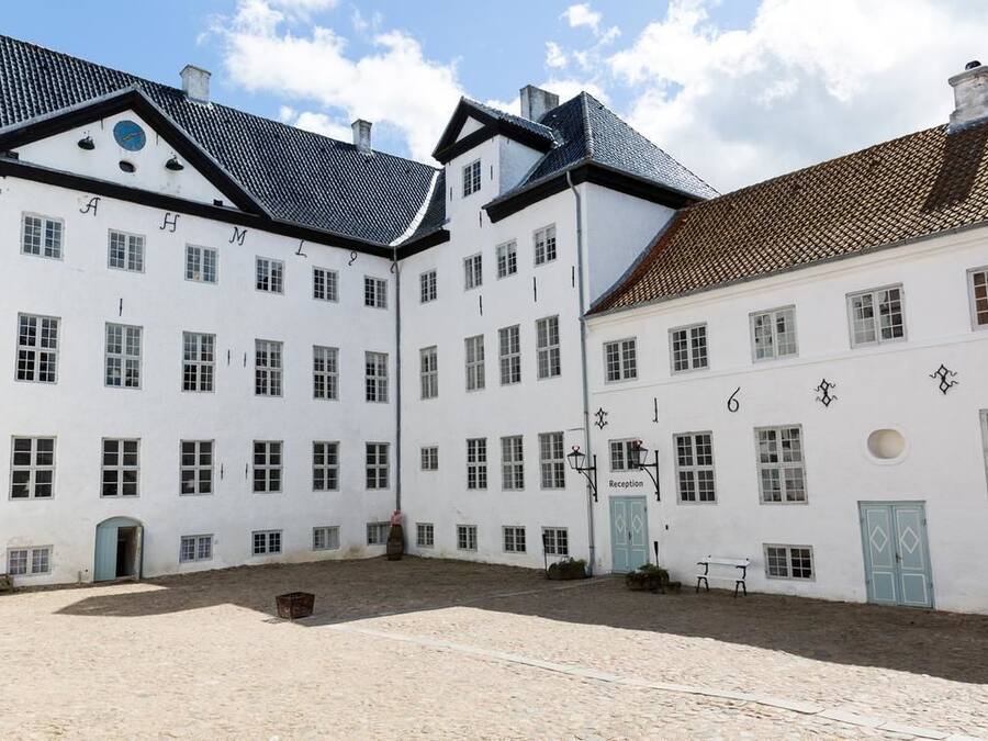 A courtyard with white buildings, a reception area, and a clock.