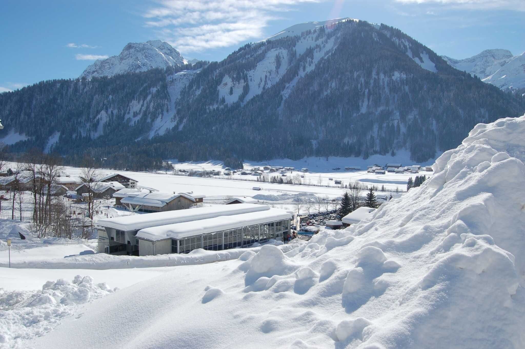 A snow-covered mountain landscape with a ski resort, including buildings and snow-covered roads.