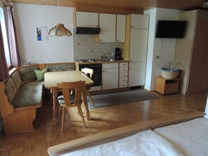 Una cocina compacta con comedor, un sofá y una televisión.