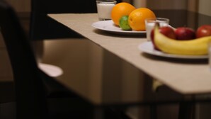 Ein Esstisch mit einer Fruchtschale, einem Glas Milch und einer Lampe im Hintergrund.