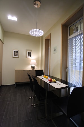 A dining area with a table, chairs, a lamp, and a fruit plate. - Dfive Apartments - Splendor (Budapest)