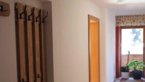 A hallway with a wooden coat rack, a door, and a potted plant. - Studio apartment - House Luxer (Auffach)