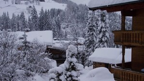 A wooden cabin surrounded by snow-covered trees and a mountainous backdrop. - Studio apartment - House Luxer (Auffach)