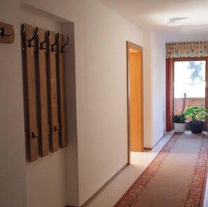 A hallway with a wooden coat rack, a door, and a potted plant.