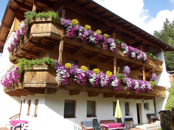 A wooden building with balconies adorned with colorful flowers and a covered outdoor seating area.