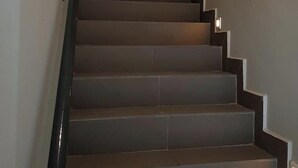 A modern staircase with a minimalist design, featuring a dark handrail and steps. - Jenjarom Boutique Hotel (Jenjarom)