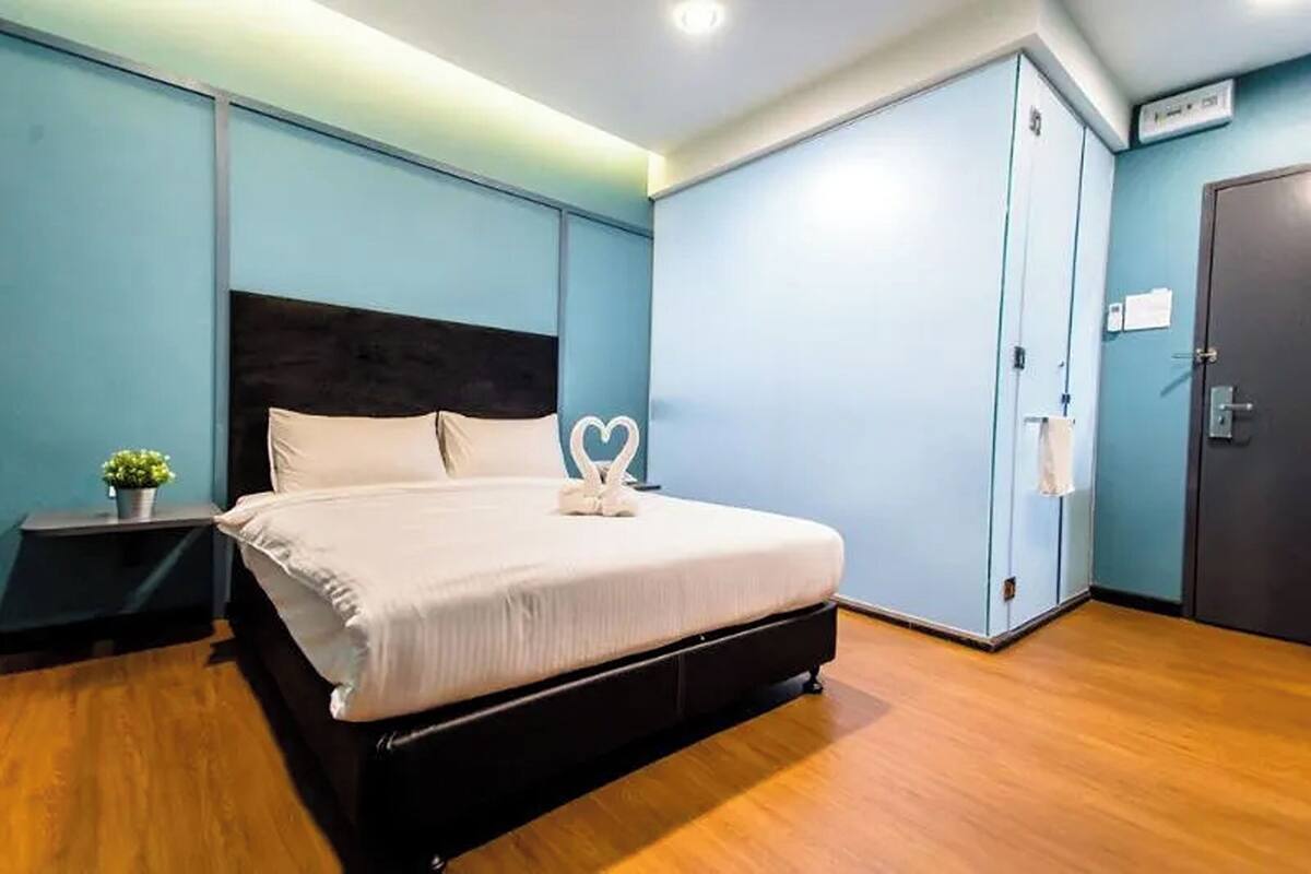 A bedroom with a bed, a nightstand, a wardrobe, and a door.