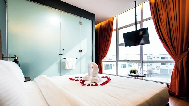 A hotel room with a bed, a TV mounted on the wall, and a window with curtains. - Jenjarom Boutique Hotel (Jenjarom)