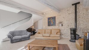 A spacious living room with a stone wall, a wooden coffee table, a grey sofa, and a beige sofa. - Beautiful home in Caderousse (Caderousse)