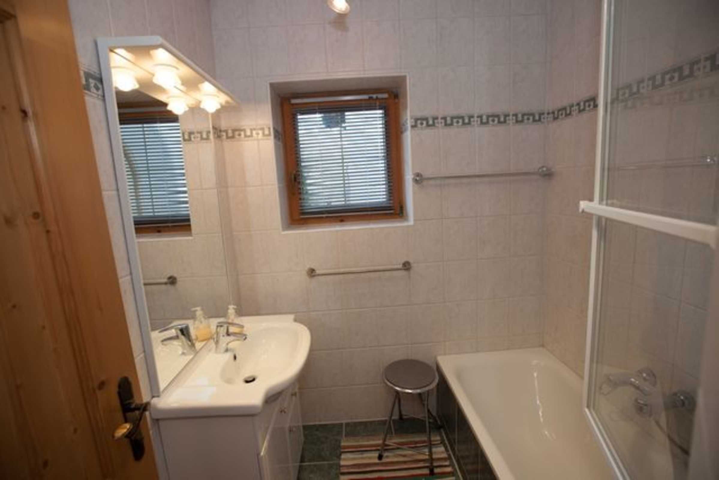 Une salle de bain équipée d’un lavabo, d’un miroir, d’une fenêtre et d’une douche.