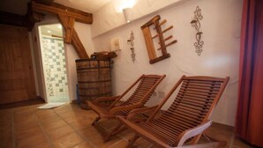 A room with two wooden lounge chairs, a wooden barrel, and a checkered floor.