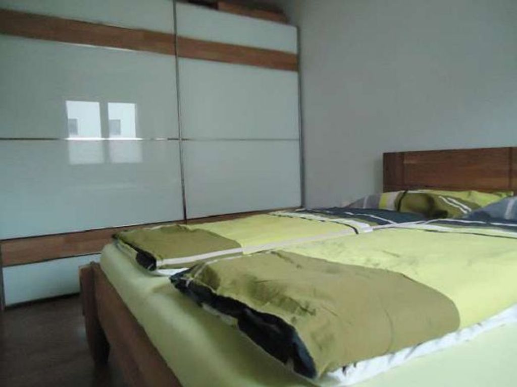 Um quarto com uma cama, um guarda-roupa e um espelho.
