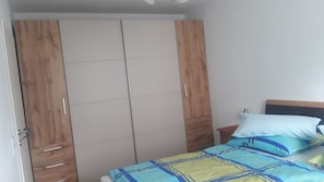 A bedroom with a bed, a wardrobe, and a bedside table. - Vacation apartment Angelika (Bad Schallerbach)