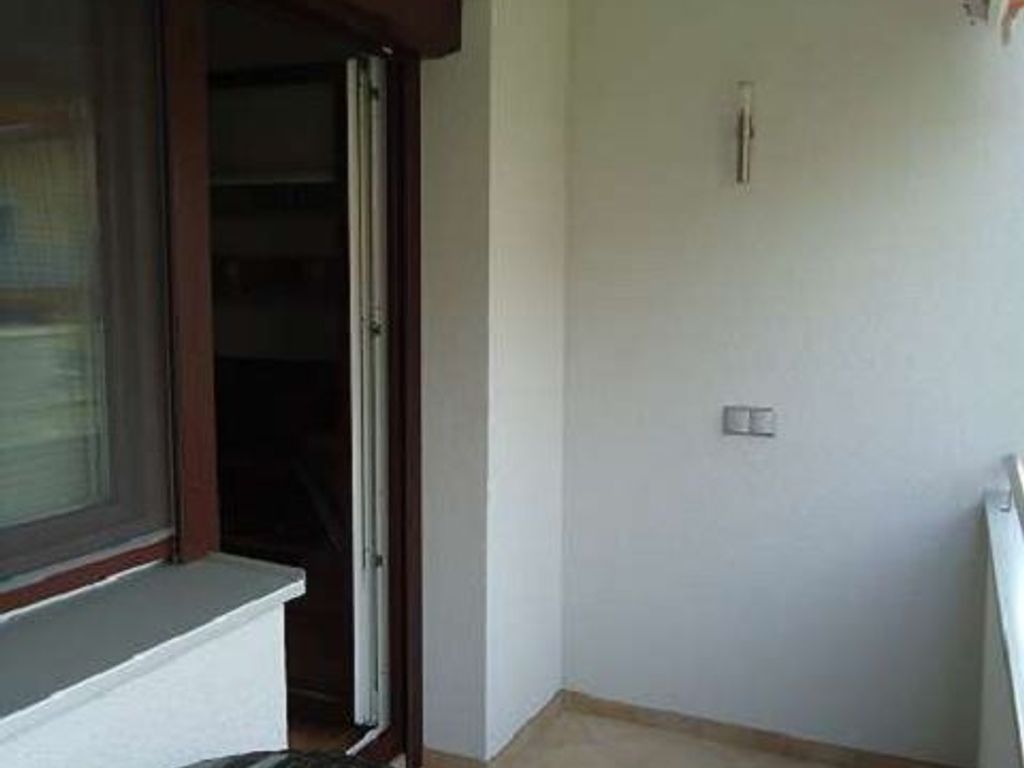 A room with a window, a door, and a light switch on the wall.