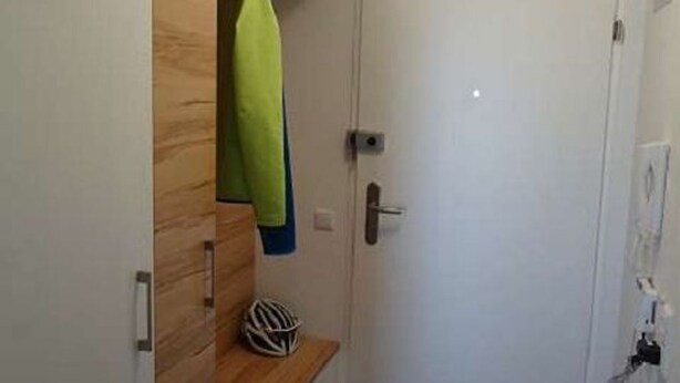 Ett rum med en trägarderob, en dörr och en liten hylla med en hjälm på.