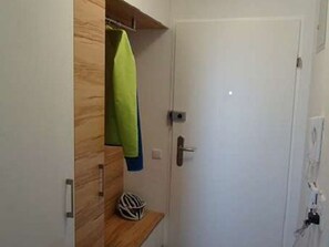 A room with a wooden wardrobe, a door, and a small shelf with a helmet. - Vacation apartment Angelika (Bad Schallerbach)