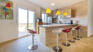 Une cuisine moderne dotée d’un îlot central, de tabourets de bar et de luminaires suspendus.