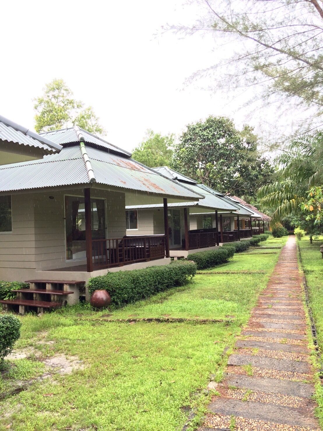A row of single-story buildings with a covered porch, a paved pathway, and a well-maintained lawn.