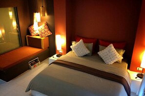 Una habitación de hotel con cama, mesitas de noche, lámparas y un espejo.