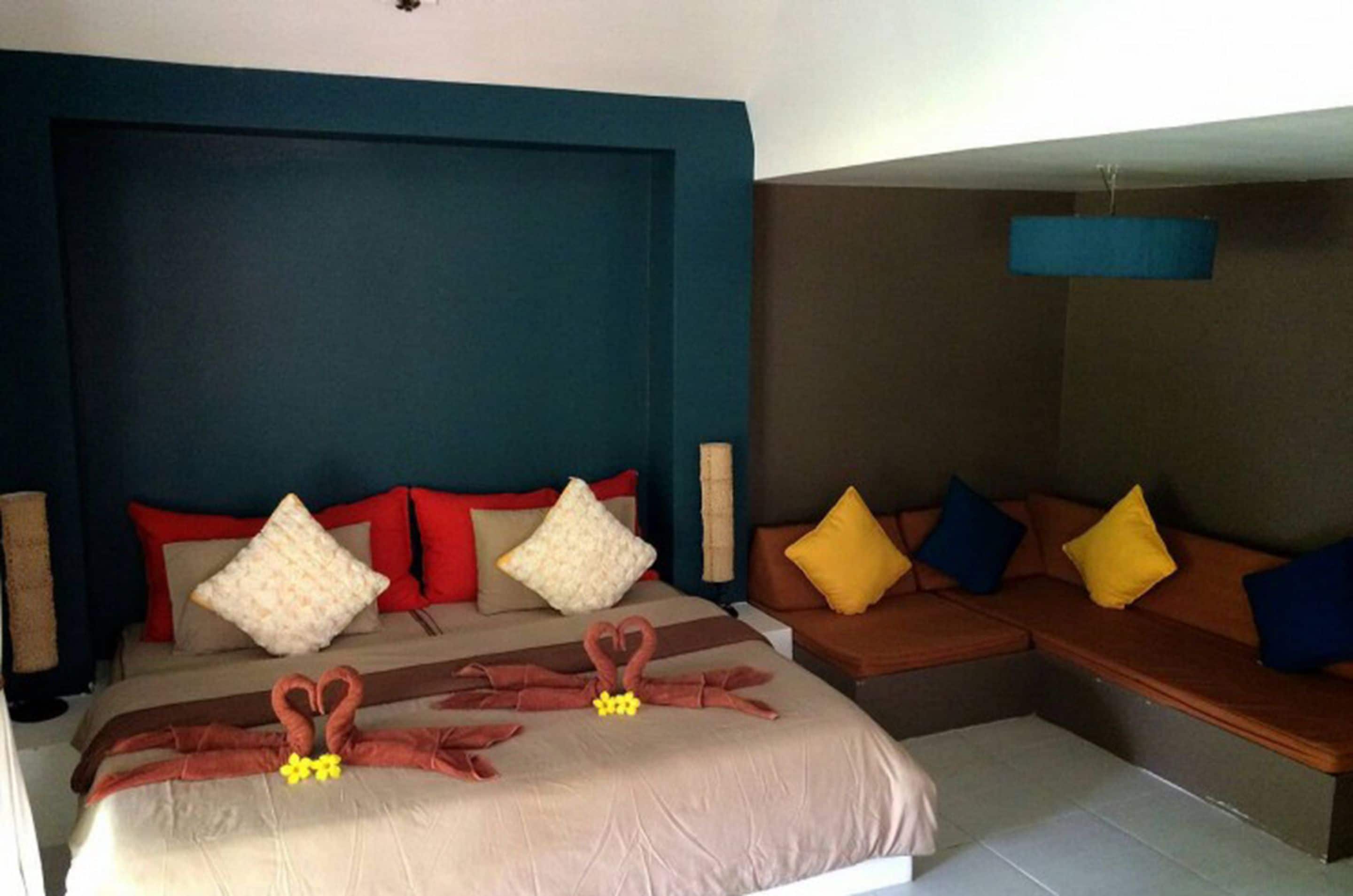 Una habitación de hotel con una cama, un sofá y una lámpara fijada a la pared.
