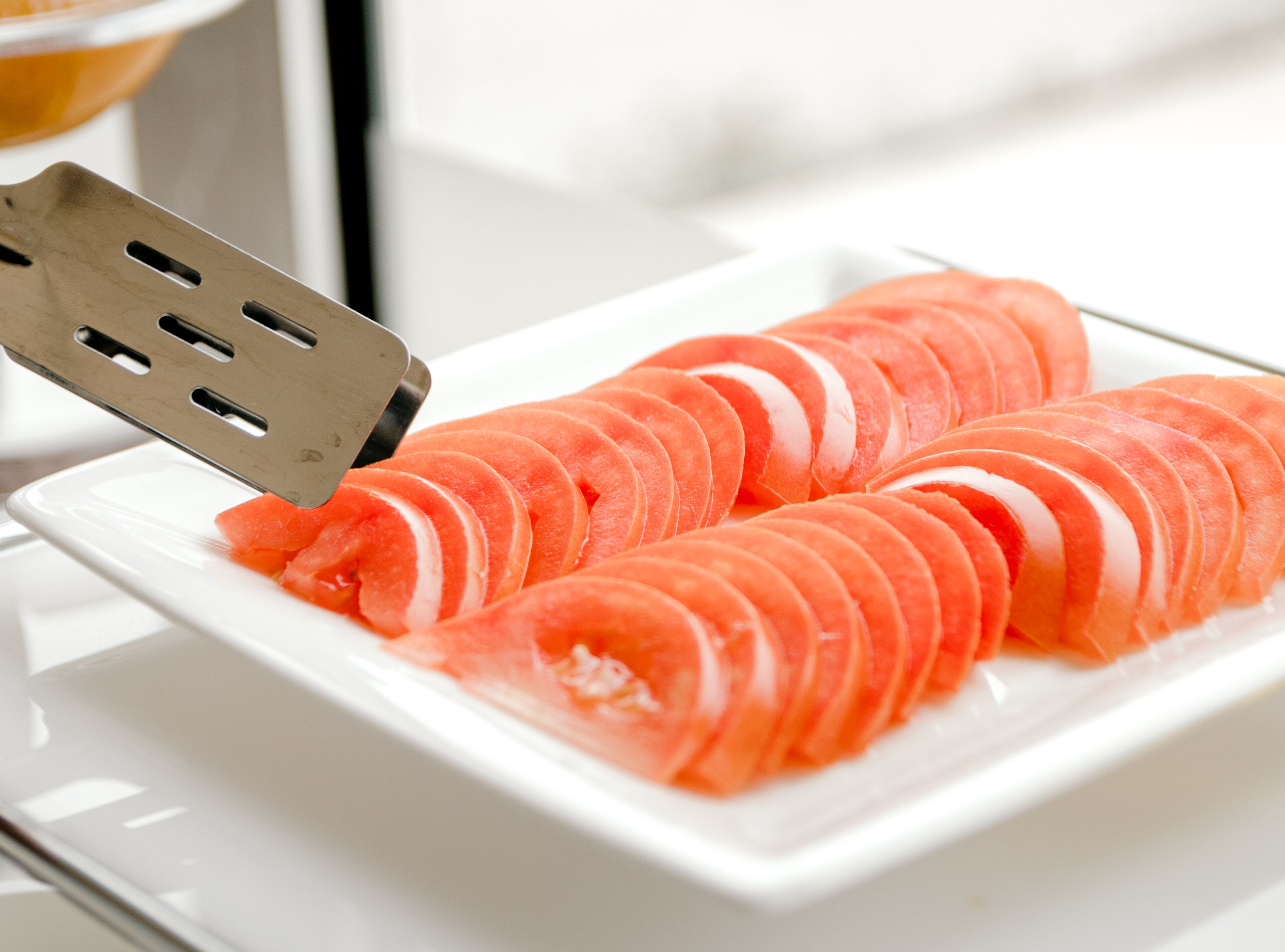 A white plate with neatly sliced salmon arranged in a fan shape.