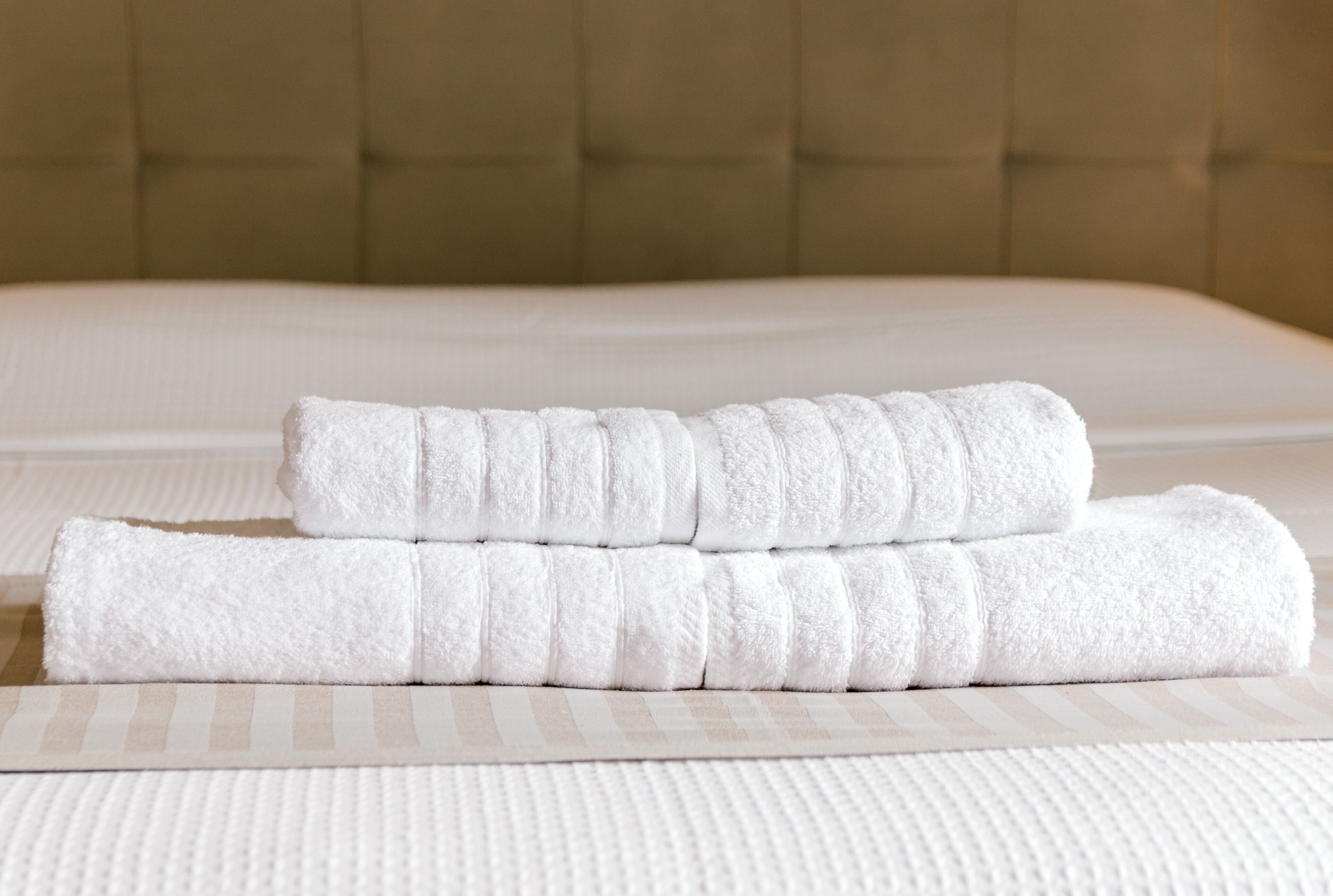 A neatly made bed with white linens and a striped pillowcase.