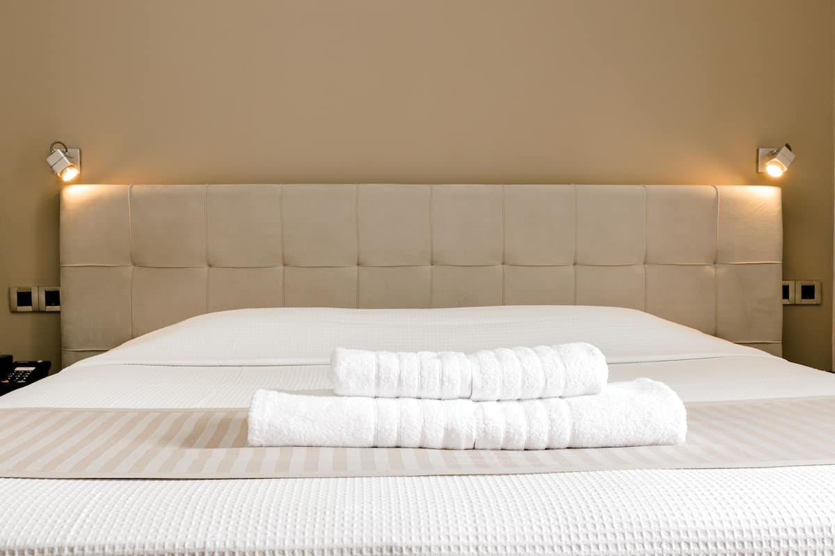 A neatly made bed with a striped bedspread and two folded towels.