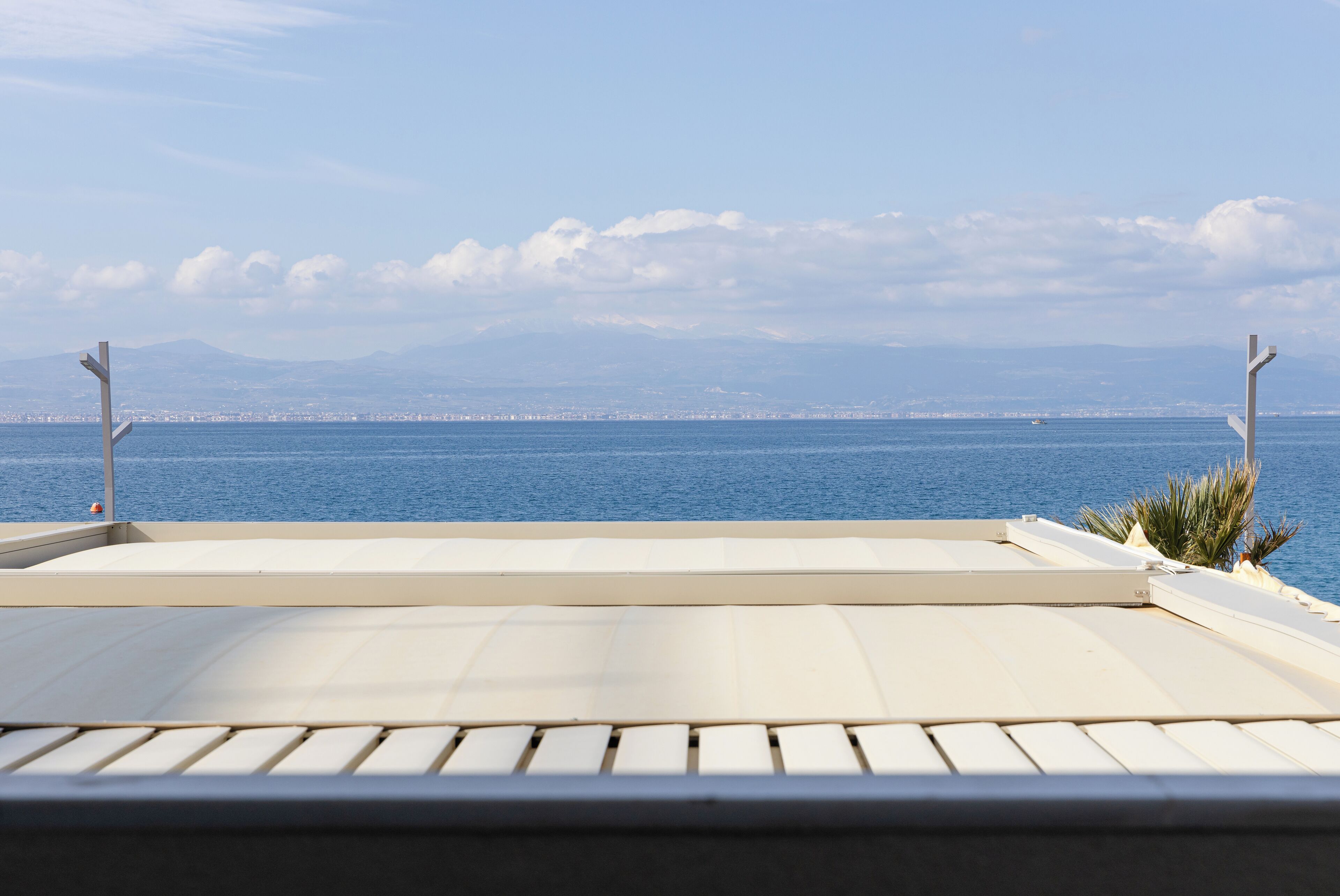 A rooftop terrace with a view of the sea and distant mountains.