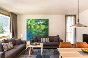 A living room with a sofa, a coffee table, a TV, and a painting of a water scene. - Holztau, Pfunds, Austria (Pfunds)