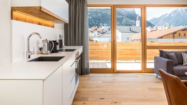 A modern kitchen with a view of a mountainous landscape through large glass doors. - Holztau, Pfunds, Austria (Pfunds)