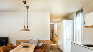 A modern kitchen with white cabinets, a wooden dining table, and a built-in bench. - Holztau, Pfunds, Austria (Pfunds)