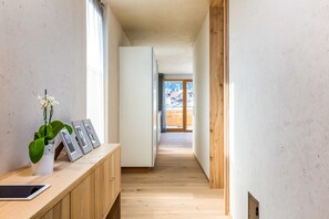 A narrow hallway with wooden flooring, a white cabinet with a tablet and framed photos, and a potted plant. - Holztau, Pfunds, Austria (Pfunds)