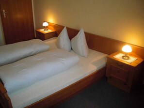 A double bed with white bedding, two bedside tables with lamps, and a wooden headboard.