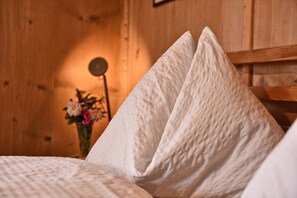 A wooden room with a bed featuring white textured pillows.