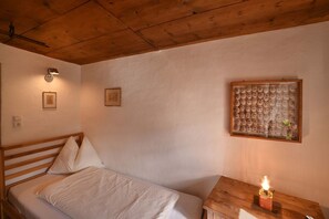 A bedroom with a wooden bed, a nightstand with a candle, and a wall-mounted light fixture.