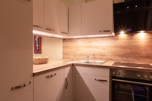 Een moderne keuken met witte kastjes, een houten aanrecht, een roestvrijstalen spoelbak en een oven.