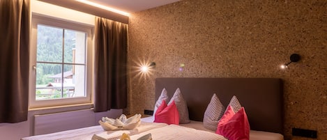 Une chambre d’hôtel avec un lit, une fenêtre avec des rideaux, une tête de lit et un mur orné d’un motif texturé.
