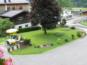 A residential area with a lawn, a dining table with chairs, and a large tree. - Künzelspitze DZ#2 - Ritter Anni - Haus Ritter (Schoppernau)