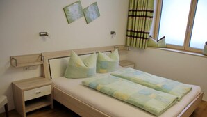 A bedroom with a bed, bedside tables, a nightstand, a window with curtains, and wall art. - Künzelspitze DZ#2 - Ritter Anni - Haus Ritter (Schoppernau)