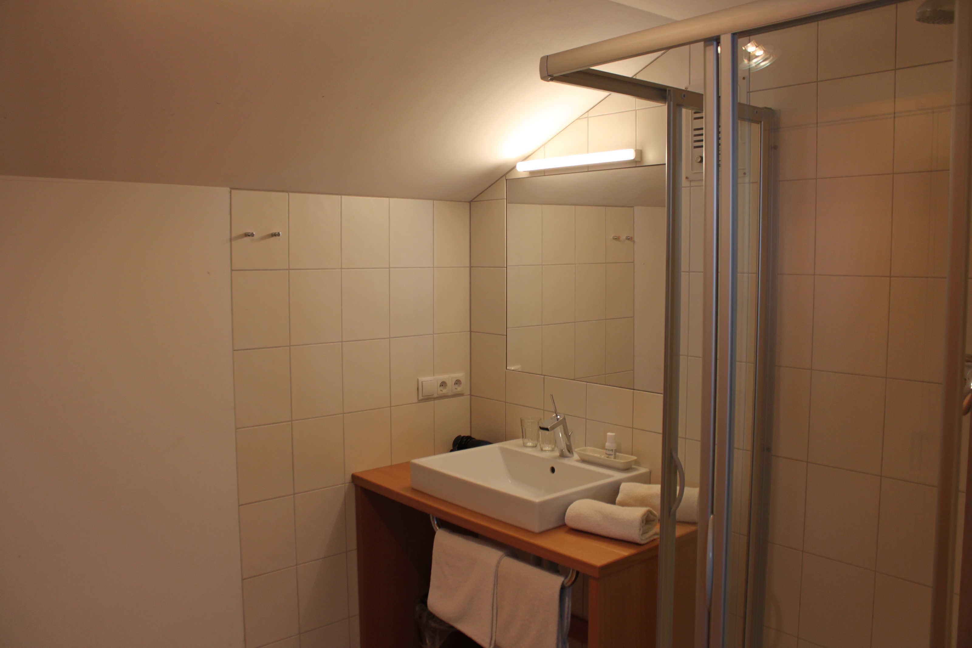 A bathroom with a sink, mirror, and glass shower enclosure.
