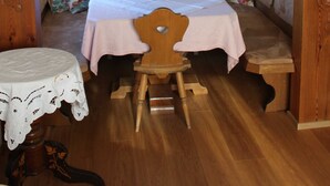 Un interior de madera con una mesa, banco y una lámpara colgante.