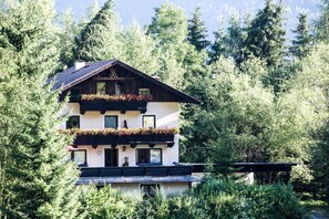 Un edificio de varios pisos con balcones, rodeado de un bosque denso.