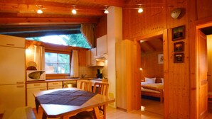 A wooden cabin interior with a kitchen, dining area, and a bedroom. - Chalet Astrid 1 - Active vacation apartments Pienz-Bobnar (Sautens)