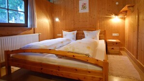 A wooden room with a bed, a window, a radiator, and a wall-mounted light fixture. - Chalet Astrid 1 - Active vacation apartments Pienz-Bobnar (Sautens)
