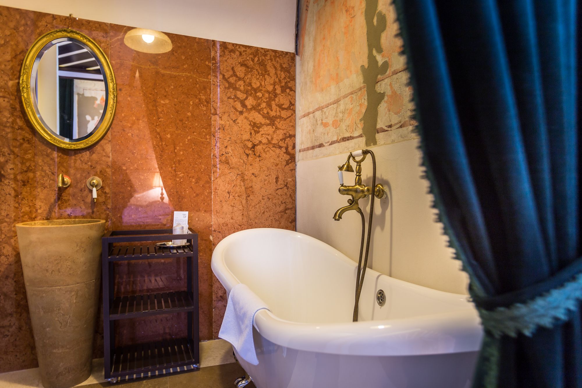 A bathroom with a freestanding bathtub, a large round mirror, and a vintage-style sink.