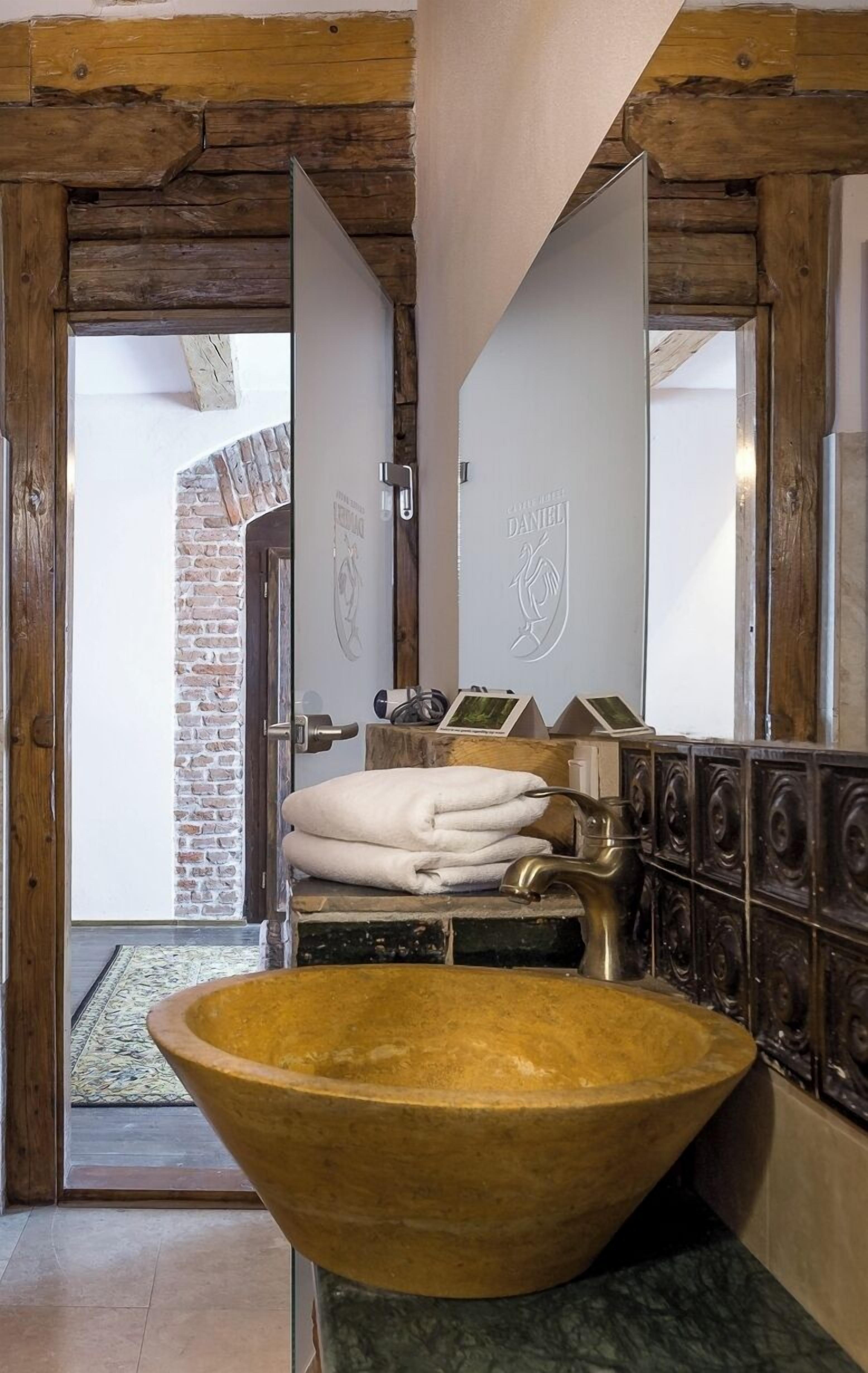 Un baño con un lavabo grande de madera, un perchero con toallas dobladas y un espejo con marco de madera.