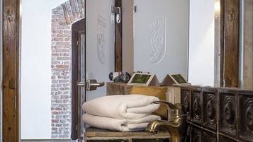 Un baño con un lavabo grande de madera, un perchero con toallas dobladas y un espejo con marco de madera.