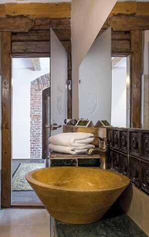 Une salle de bain avec un grand lavabo en bois, un porte-serviettes avec des serviettes pliées et un miroir avec un cadre en bois.