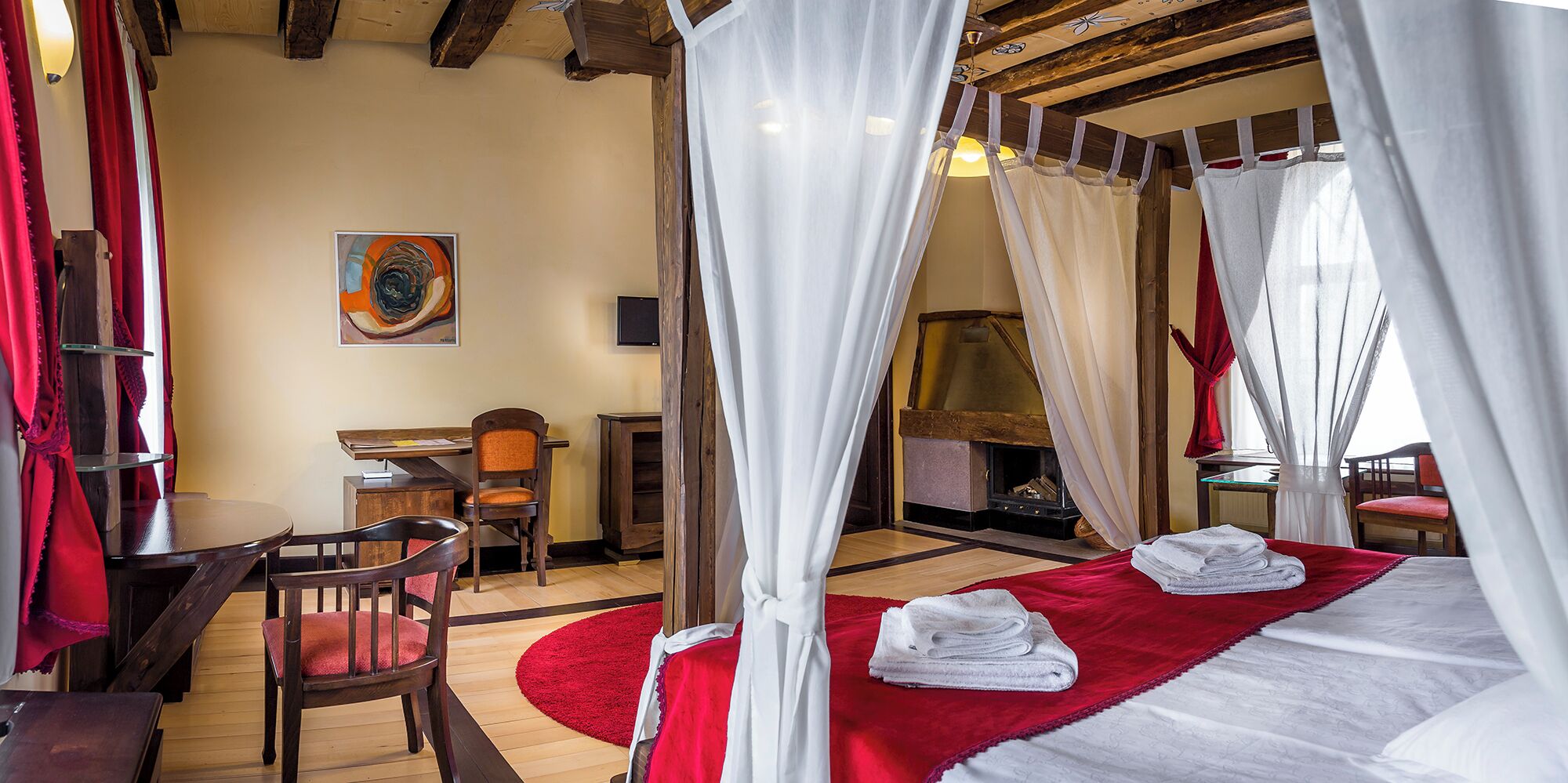 Ein gemütliches Zimmer mit einem Bett, einem Schreibtisch und einem Kamin.